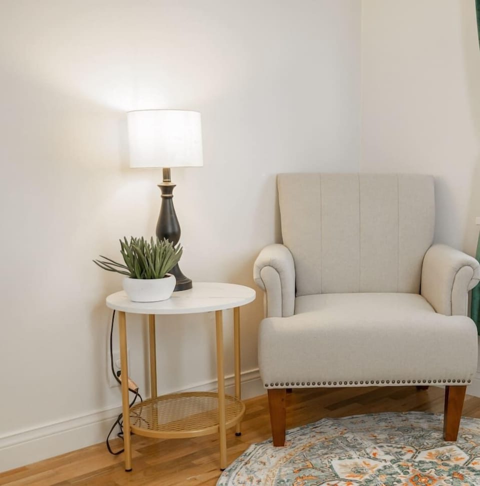 Cozy reading corner with armchair, side table, and soft lighting.