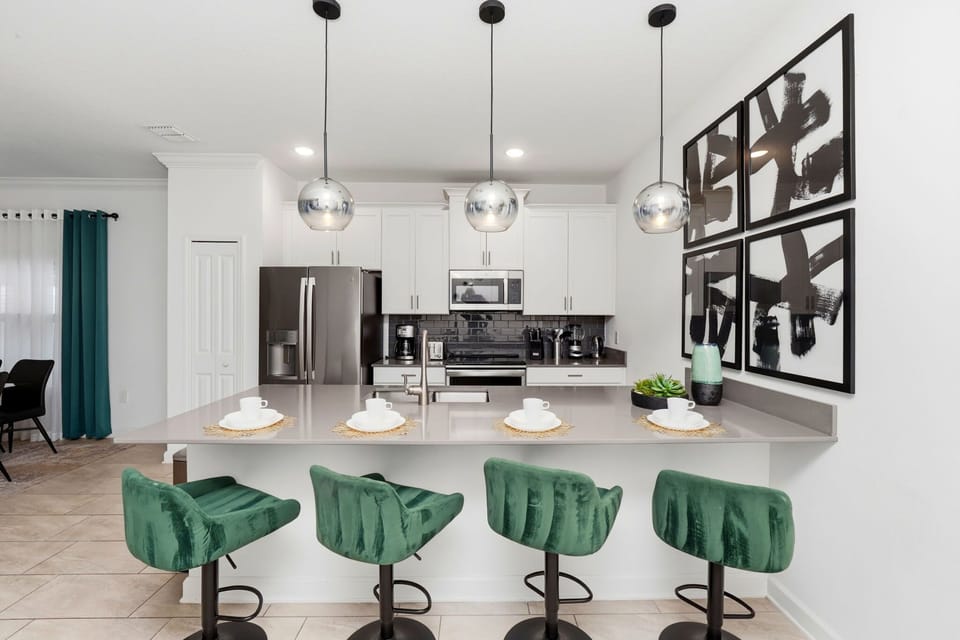 Modern kitchen with a large island and green velvet bar stools for casual dining.