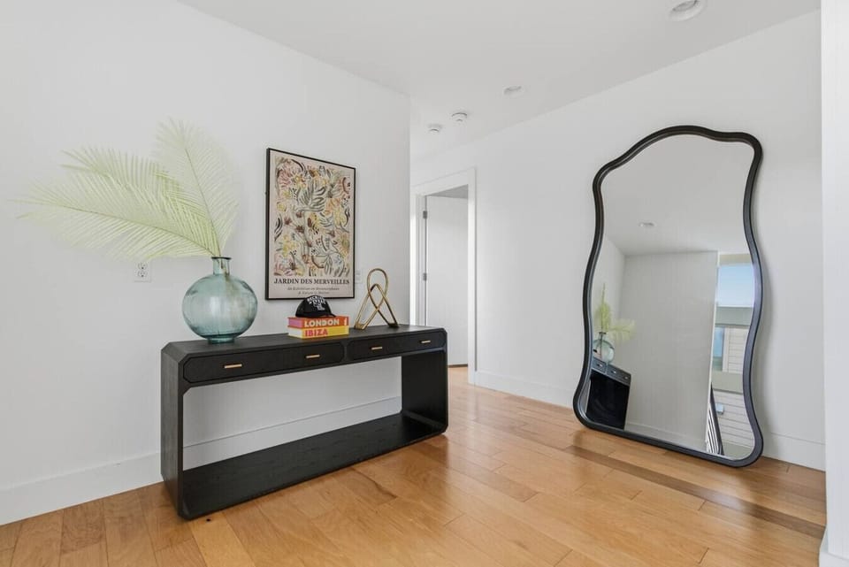 Stylish entryway vignette featuring a decorative console table, curated artwork, and a full-length mirror
