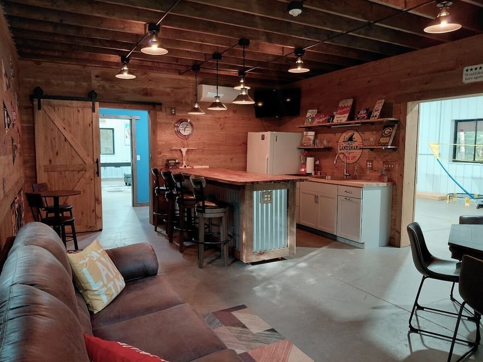 The Speakeasy with a full-size bar, couch, two flat screen TVs, and poker table