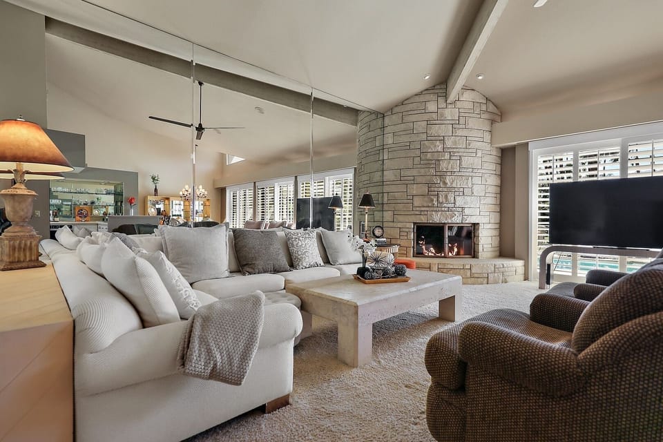 Living room with large couch and chairs around a cozy curved stone gas fireplace