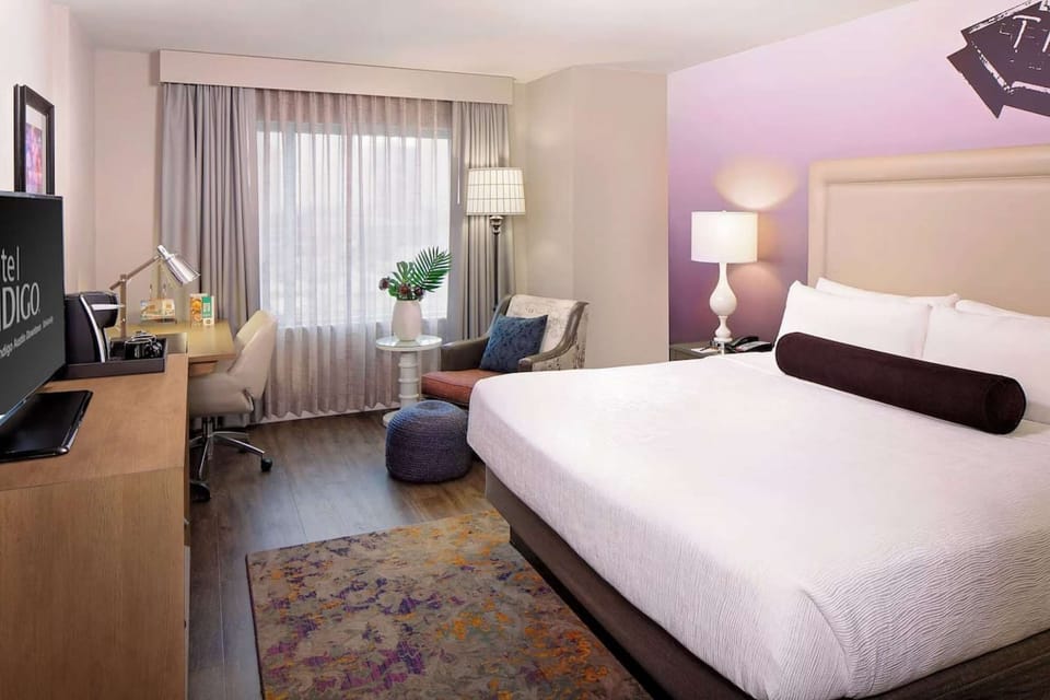 King bed, soft chair by window, desk, and relaxing vibe