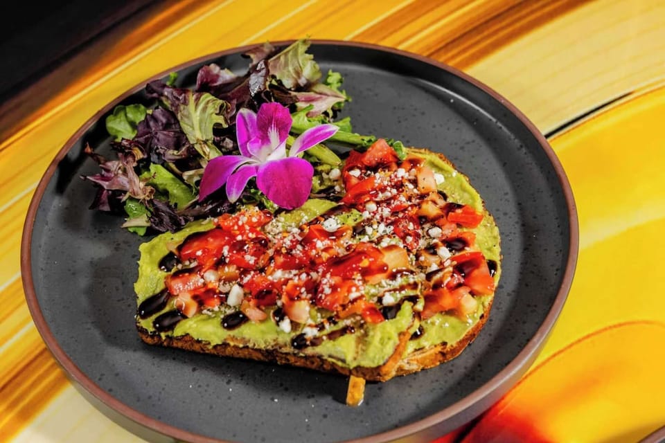 Toast with avocado, tomatoes, balsamic glaze, and fresh greens