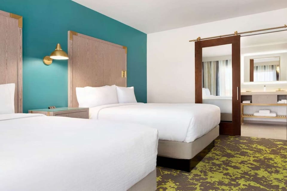 Two queen beds with teal wall and reading lights