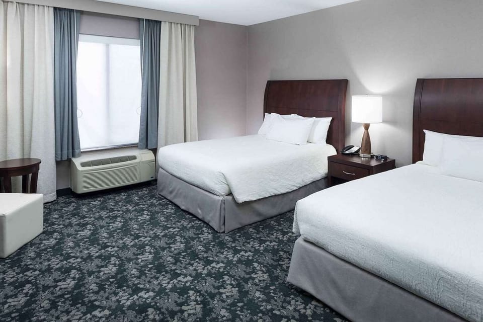 Two queen beds with soft linens and bedside lighting