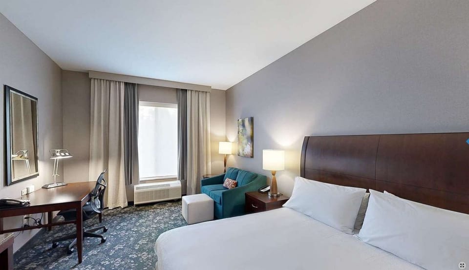 Bright bedroom with desk, chair, and seating by the window