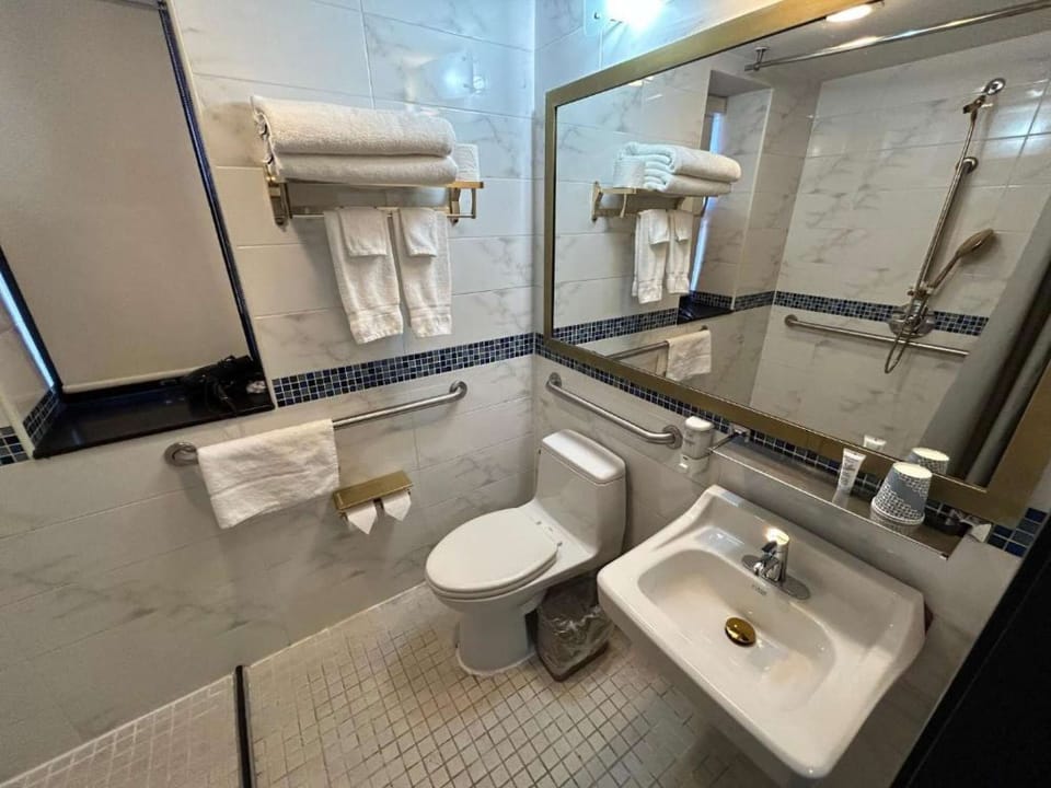Bathroom with large mirror, towels, tiled walls, and accessible fixtures.