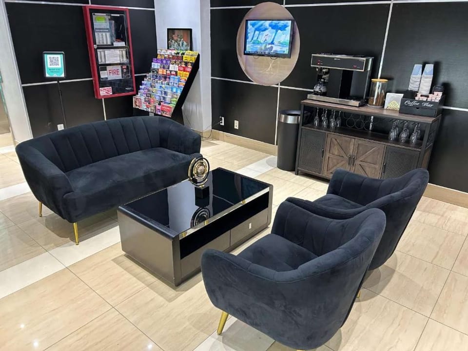 Seating area with dark chairs, sofa, and TV near the coffee station.