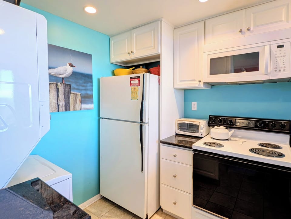 908 Dover Sea Colony East Modern Kitchen - Updated kitchen at 908 Dover, Sea Colony East, featuring white cabinetry, modern appliances, and vibrant coastal blue walls.
