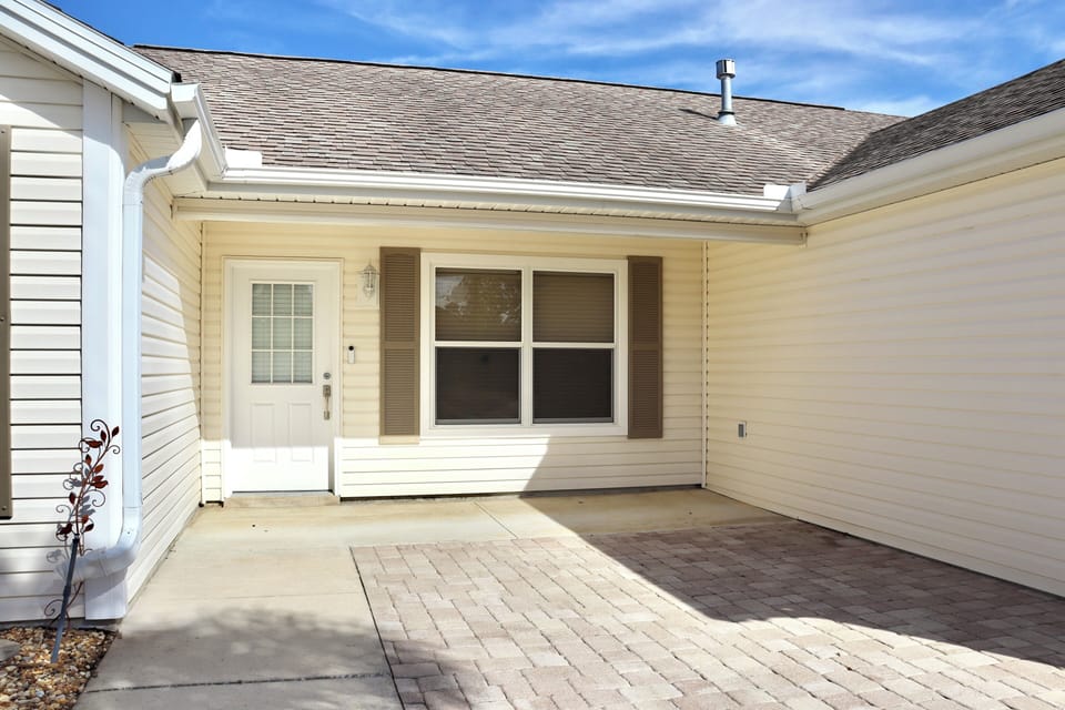 Single-story vacation rental with covered entrance and private courtyard area featuring brick paver flooring.