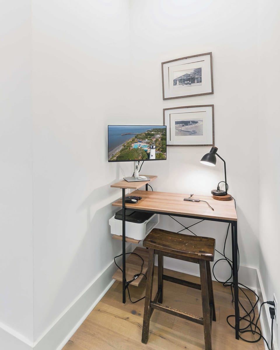 Your private workspace awaits with coastal views displayed on screen, inspiring seaside artwork, and warm task lighting for productive moments.