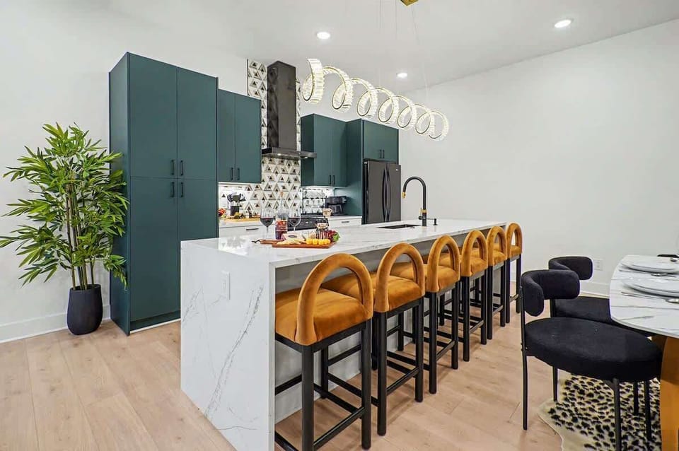 2nd Floor: Fully equipped kitchen with green cabinetry, marble countertops, black appliances, and a striking waterfall island offering bar seating for 6.