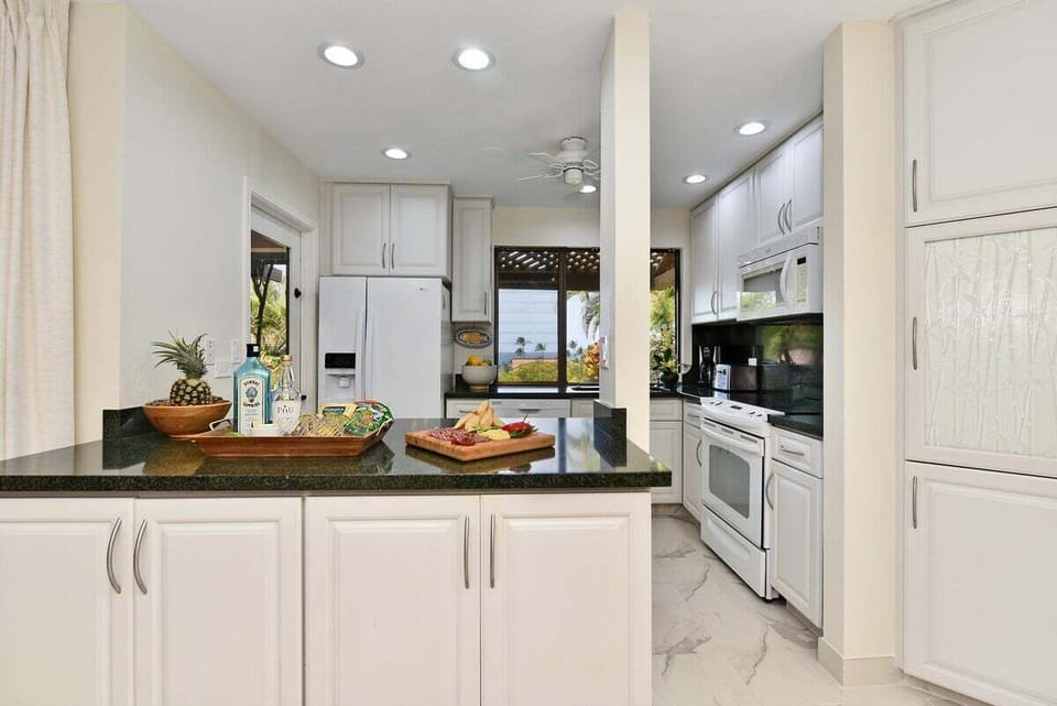 A beautifully lit kitchen with white cabinetry, polished granite counters, and an open layout that feels airy and inviting.