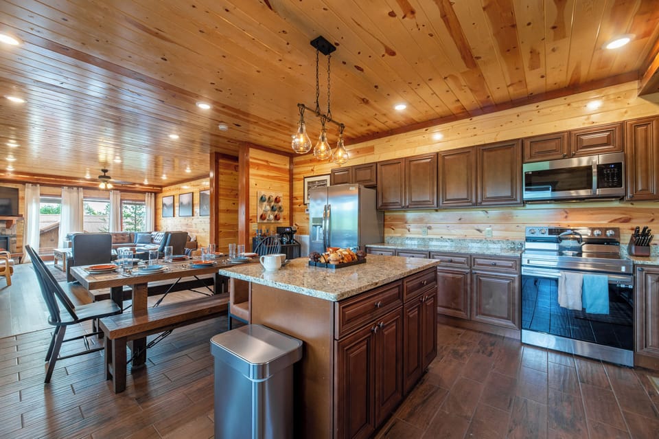 This fully equipped cabin kitchen features granite countertops, warm wood cabinetry, and a spacious island perfect for cooking and gathering.