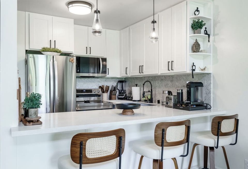 Your modern kitchen awaits with sleek white cabinetry, stainless appliances, and a spacious breakfast bar perfect for morning coffee or evening conversations.