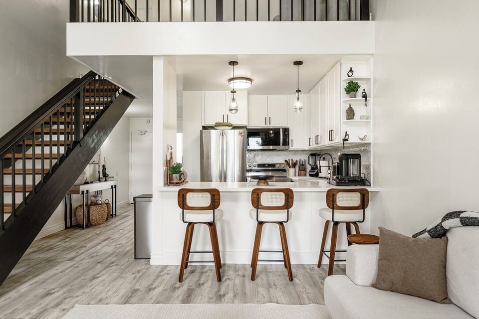 Your modern open-concept space blends style and function with sleek white kitchen, breakfast bar, and stylish staircase.