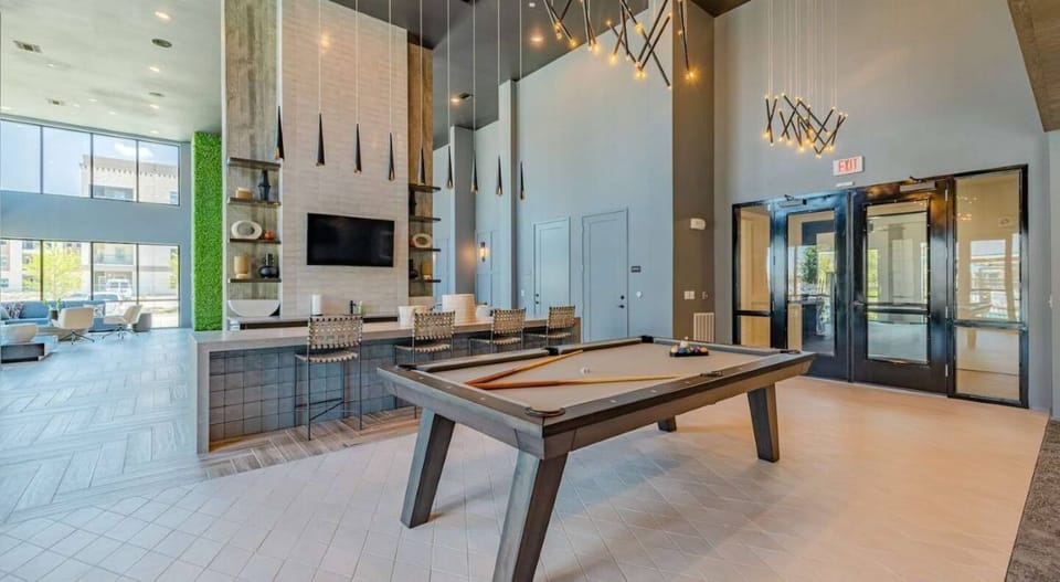 Chic clubhouse: pool table, bar seating, TV, and soaring ceilings