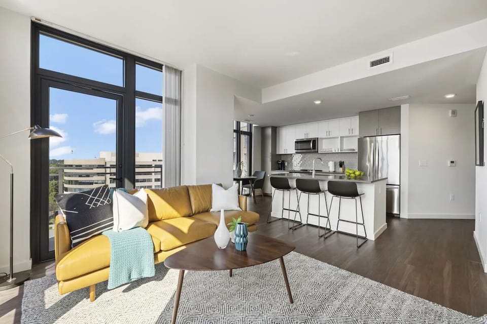Gather on the cozy sofa beside a bright open kitchen.