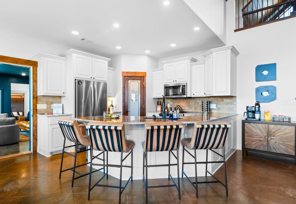 Bright white cabinetry, stainless appliances, and a generous island make this kitchen both beautiful and fully equipped for your stay.