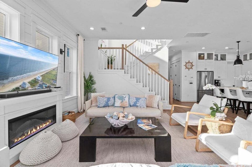 Coastal living area featuring modern fireplace, plush seating, and open staircase design