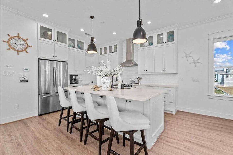 Chef's kitchen featuring double ovens, large prep island, and modern pendant lighting.