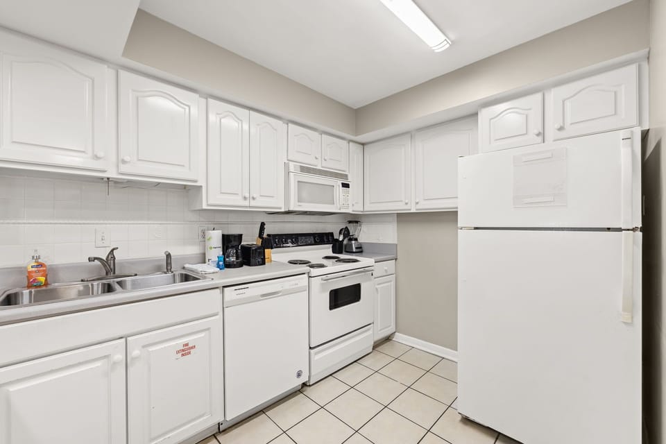 Compact kitchen with white cabinetry and essential appliances for convenient cooking.