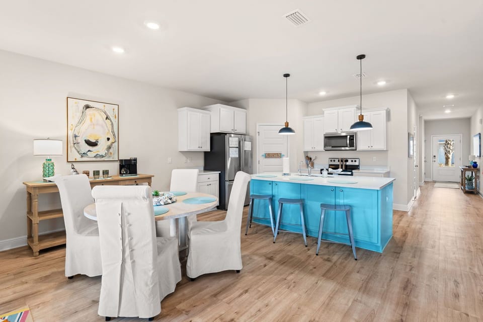 Your modern kitchen features a bright turquoise island and pendant lighting, creating the perfect space for cooking and casual dining together.