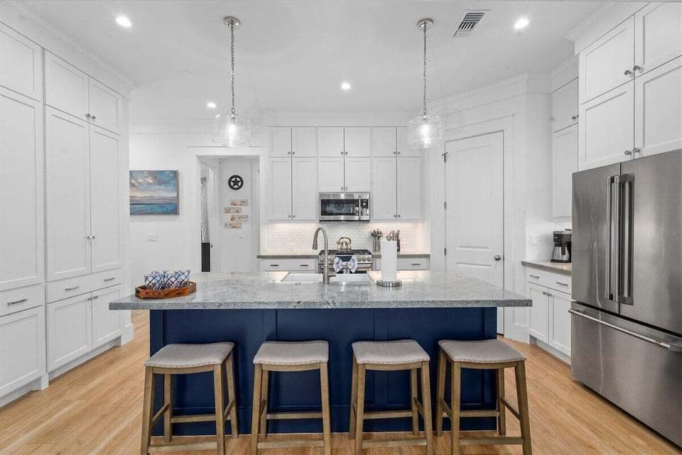 Modern kitchen with large island, bar seating, stainless steel appliances, and ample prep space for group meals.