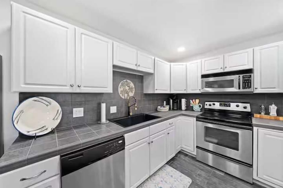 Modern kitchen with stainless steel appliances and white cabinetry.