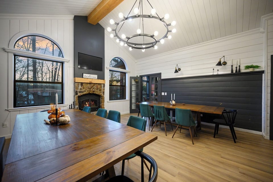 Gather around rustic wood tables in this elegant dining space, where cozy fireplace warmth meets modern style beneath soaring ceilings.