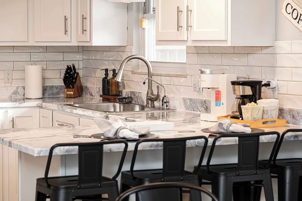 This view shows the seamless flow from the kitchen to the dining area and wood-paneled sunroom. Enjoy easy access to the coffee machines for your morning brew and plenty of extra seating at the large table and lounge for the whole group.