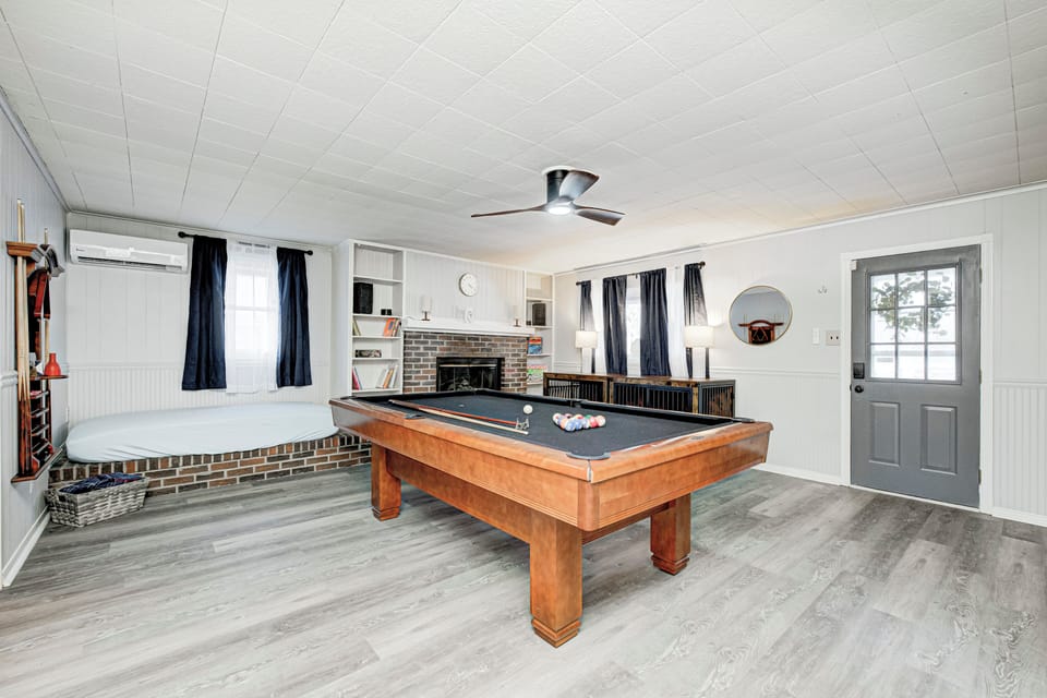 Bright game room with pool table, cozy lounge, brick fireplace, and modern style