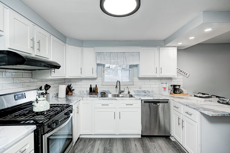 Modern kitchen with white shaker cabinets, stainless appliances, and subway tile