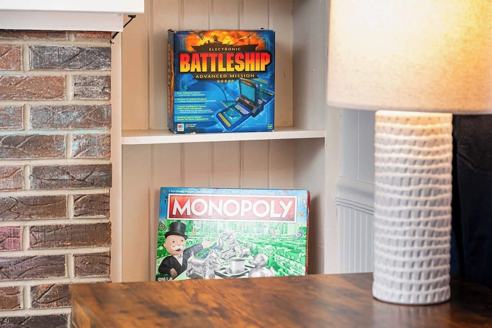 Relax by the brick fireplace, featuring built-in shelves stocked with board games and a poker chip set. This cozy nook blends classic charm with modern fun, offering an inviting retreat for guests of all ages.