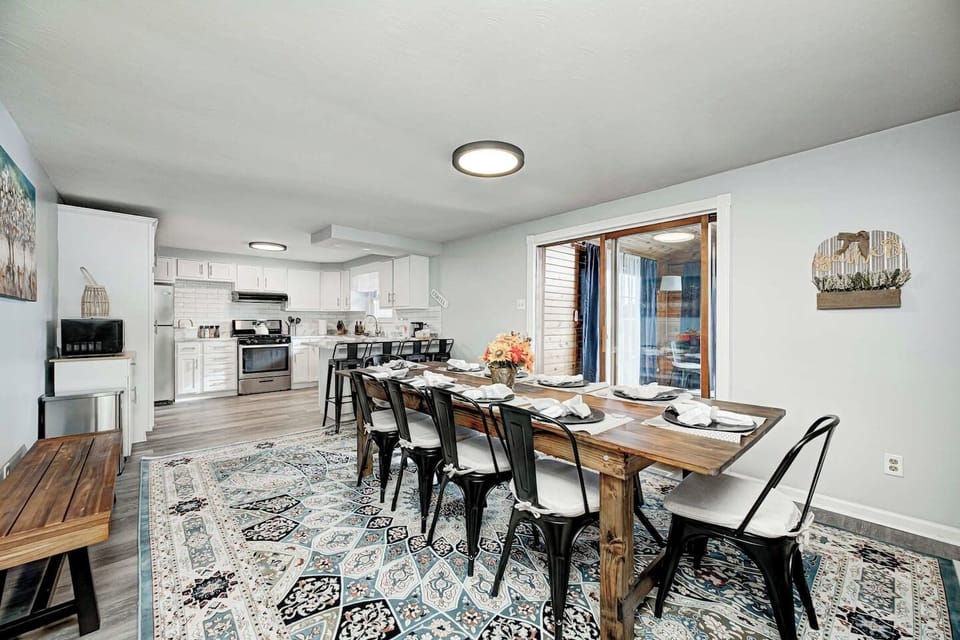 This view highlights the seamless flow between the living and dining areas. Large windows and soaring ceilings fill the space with natural light, making the home's central hub feel incredibly airy and spacious.