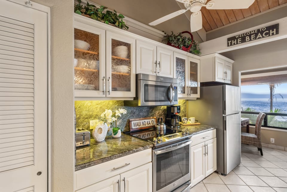 Fully equipped kitchen with stainless steel appliances, granite countertops, and tropical garden views