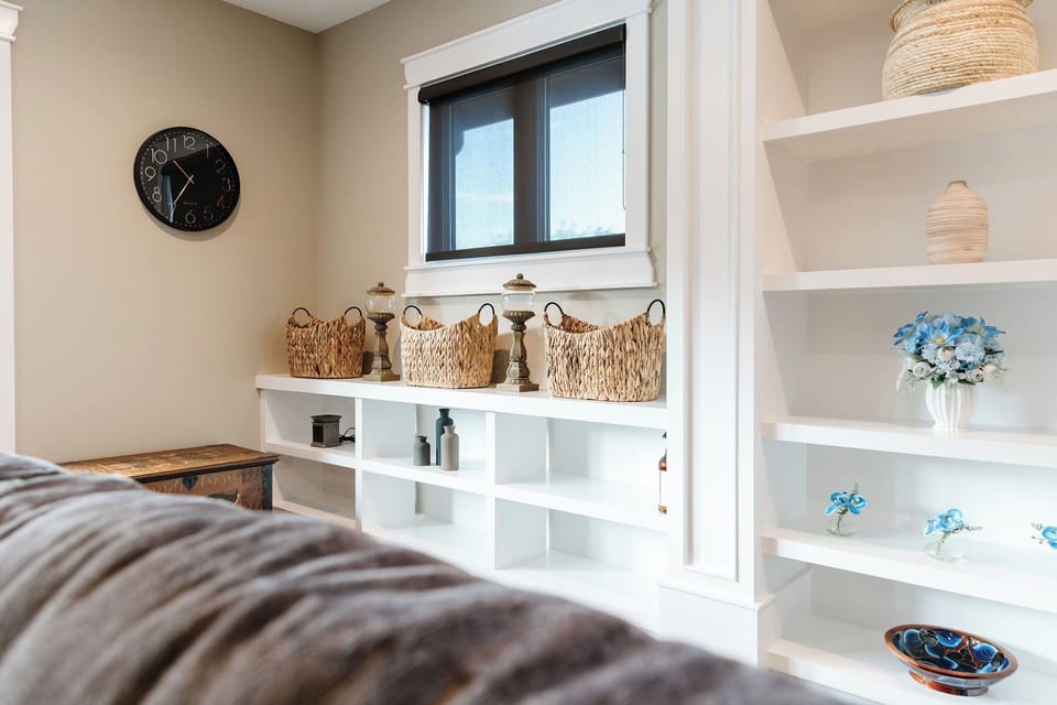 This compact laundry closet features a stacked white washer and dryer, with light brown tile floors and white walls. Wooden doors to the left and right offer access to additional rooms, adding convenience.