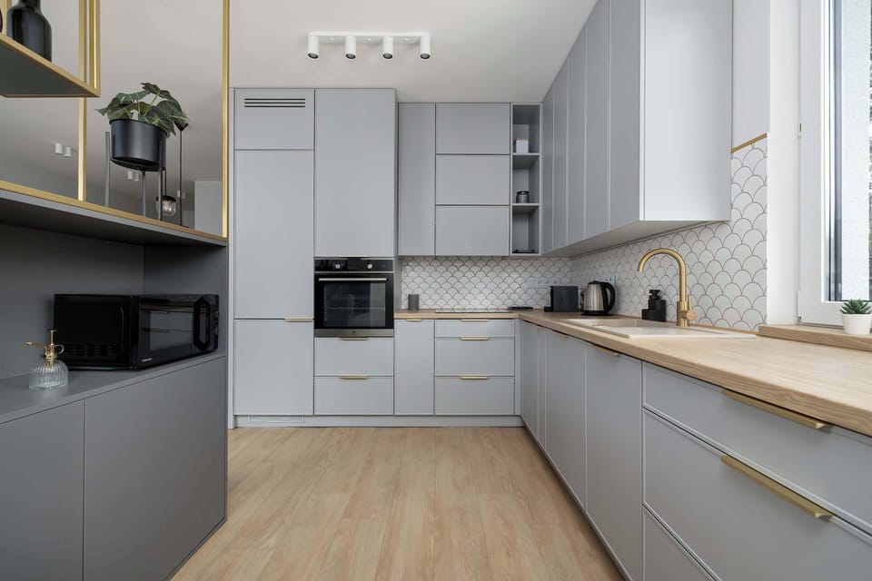 A modern kitchen in shades of gray with a wooden countertop, equipped with high-end appliances and a coffee machine.