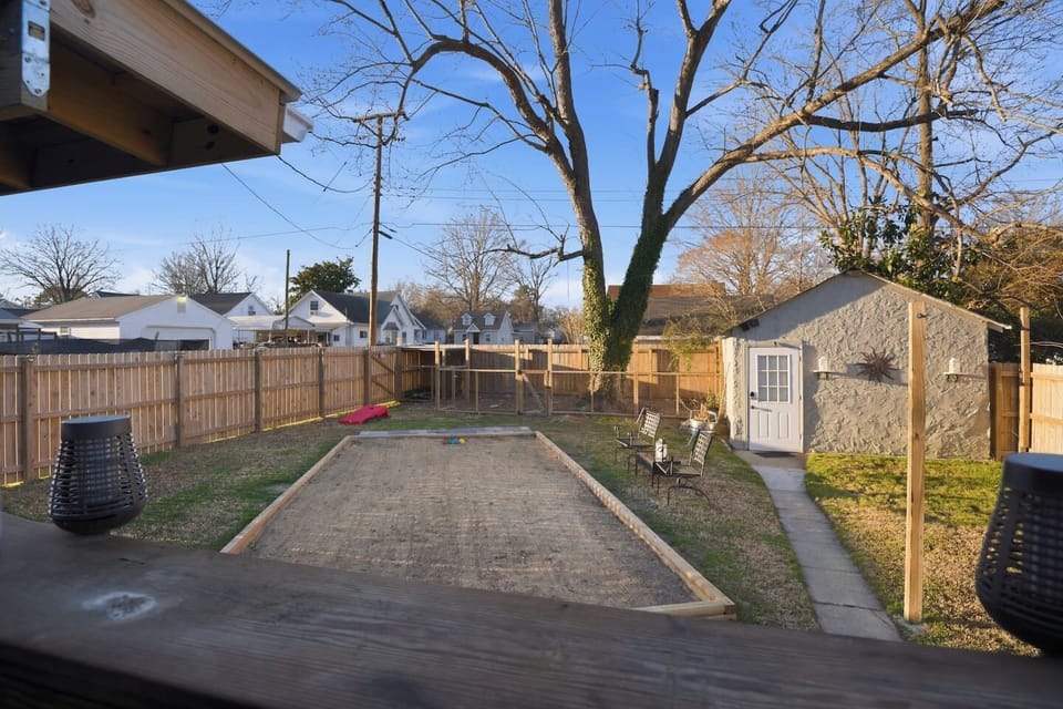 Outside, enjoy grilling out— a full sand bocce court, cornhole stations, an outdoor shower, bar seating, and a fenced dog kennel all make this fully fenced haven an oasis for your leisure!