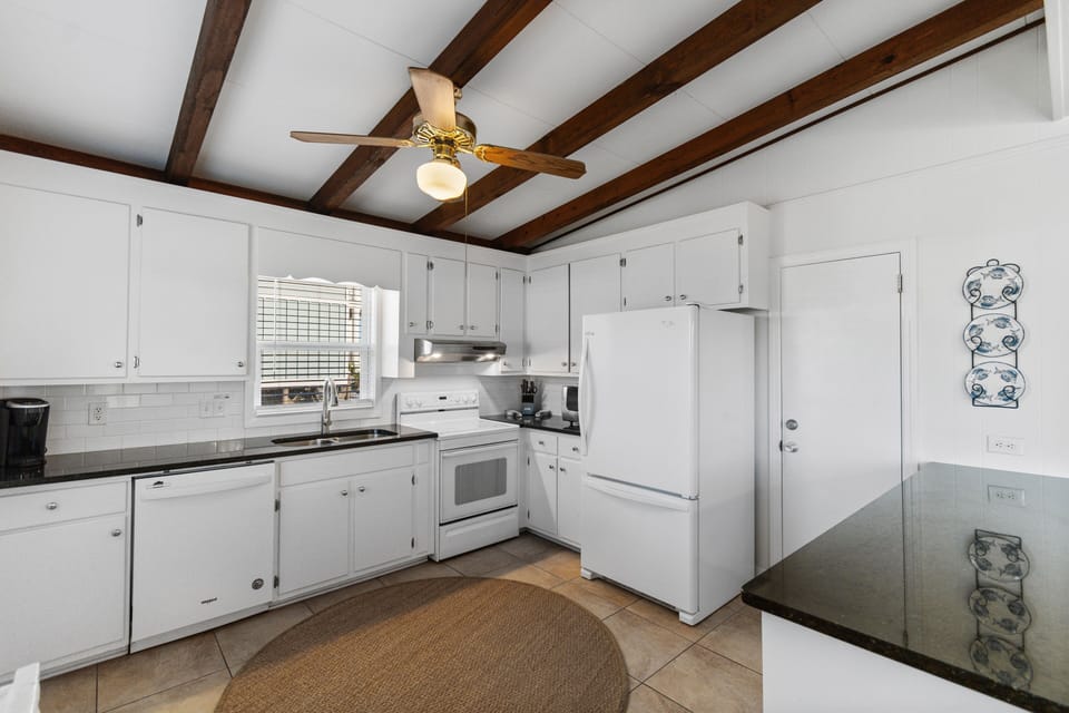Cook your favorite meals in this fully-equipped kitchen featuring exposed wooden beams, white appliances, and ample counter space for your culinary adventures.
