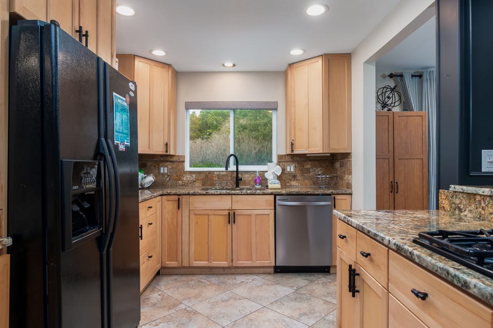 Step into your fully equipped kitchen featuring granite countertops, stainless steel appliances, and warm wood cabinets for memorable home-cooked meals.