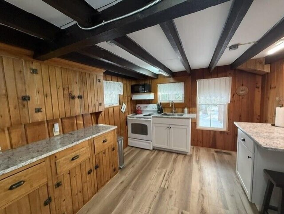 Your rustic kitchen blends exposed beams with modern appliances, creating a cozy cooking space where granite counters meet charming wood cabinets.