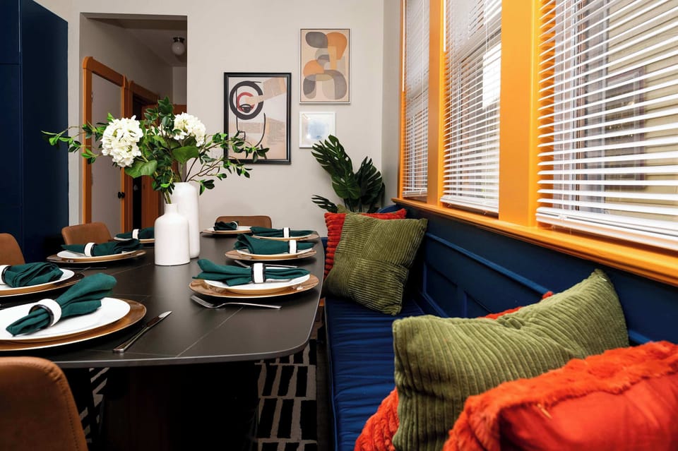 Bright dining nook with colorful pillows, modern table settings, and cozy bench seating—an inviting spot for group meals, game nights, and relaxed conversations