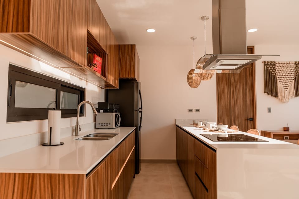 A fully equipped kitchen featuring an induction stovetop, refrigerator, and microwave.