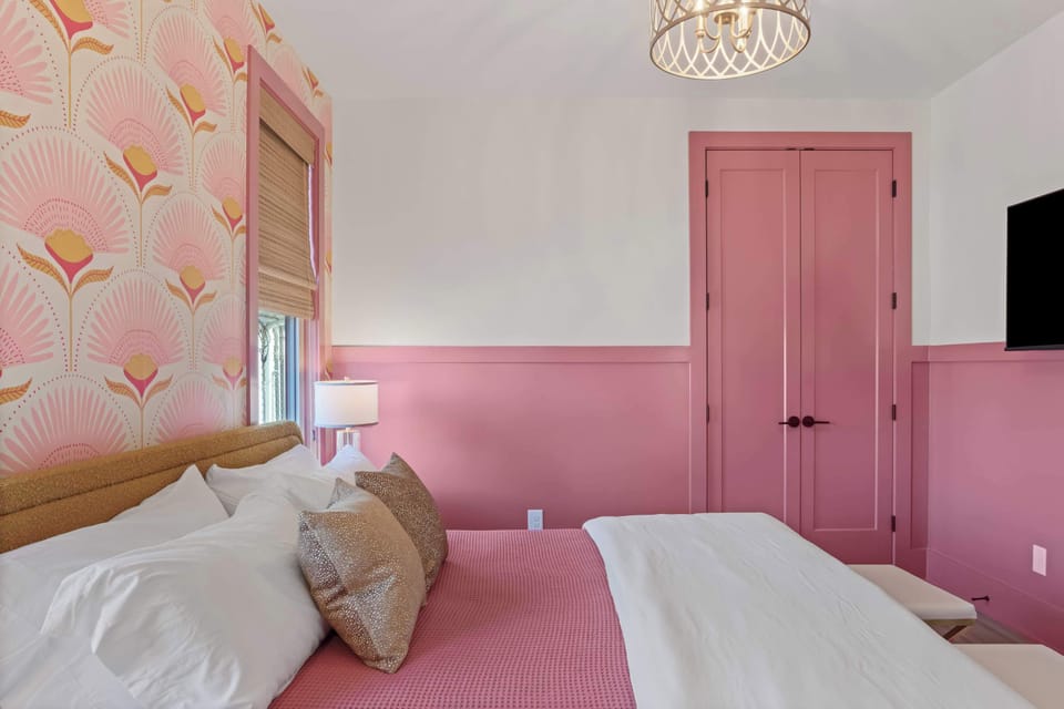 Another view of the primary bedroom highlighting the bold pink wainscoting, custom details, and serene sleeping space.