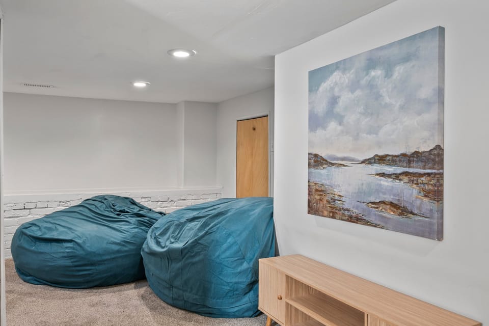 Downstairs via a twisting carpeted staircase is the Grotto.  A 6' high finished room with large bean bag chairs sofa, Smart TV and lots of room for teen or kid gatherings, gaming, games, sleepovers, etc.
