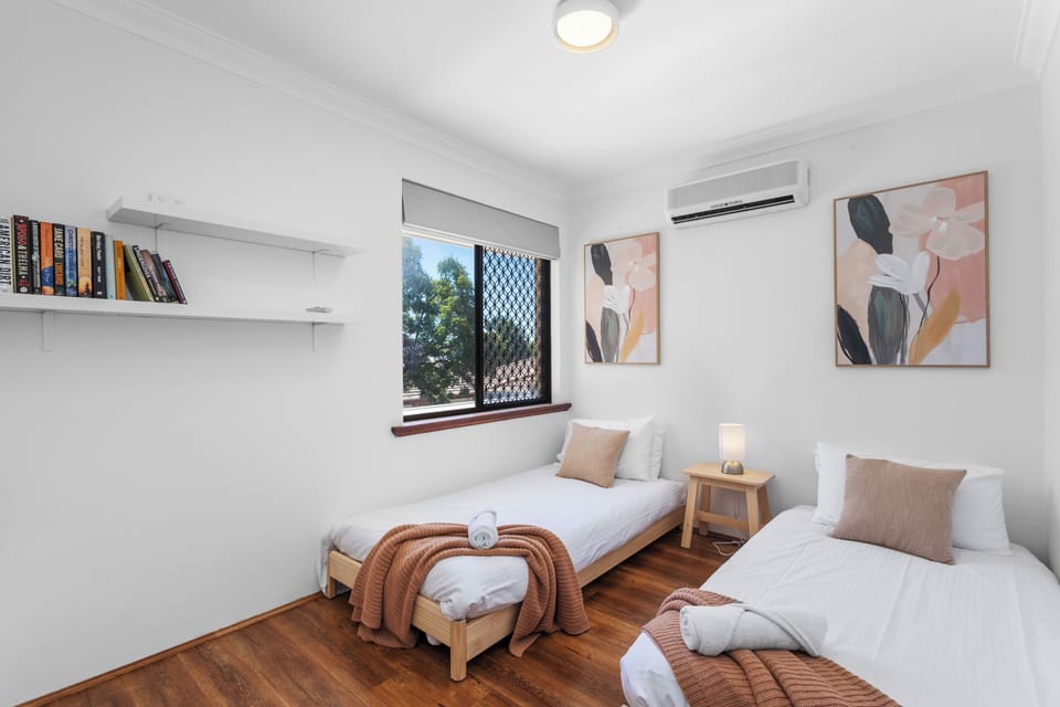 A relaxing twin bedroom designed for comfort, featuring two single beds, calming decor, and plenty of natural light.