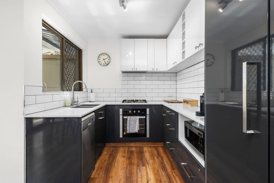 Bright and stylish kitchen featuring white and gray finishes, complete with appliances and cookware for easy cooking during your stay.