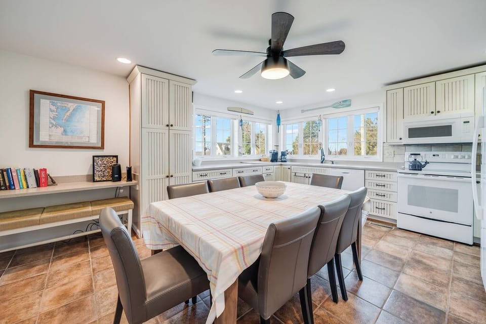 Gather around your spacious dining table where morning coffee and evening meals become cherished memories in this bright, well-equipped kitchen.