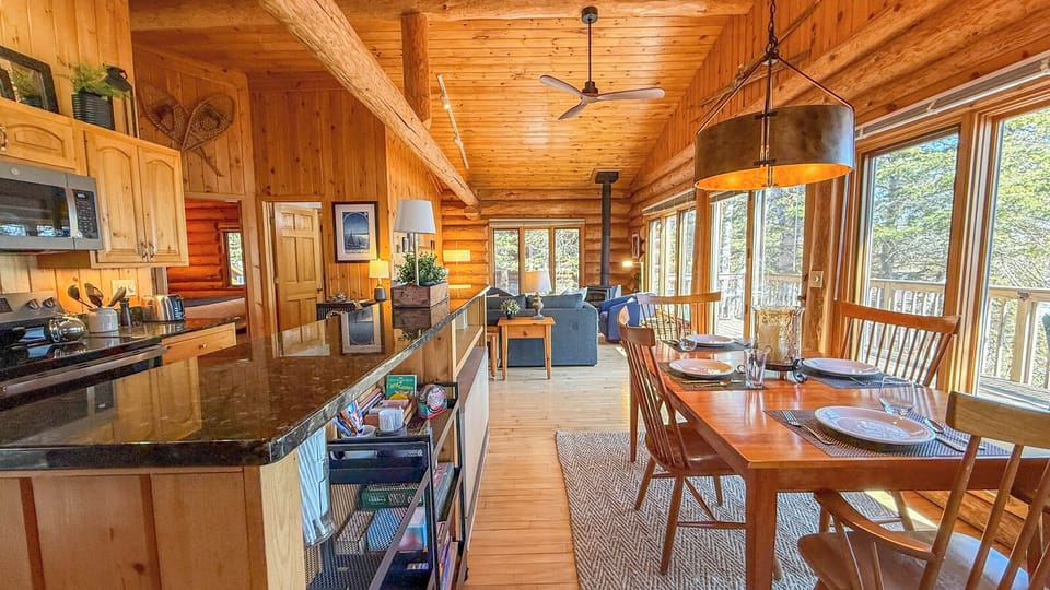 Warm wood surrounds you in this cozy cabin where natural light streams through windows, creating the perfect space for cooking and dining together.
